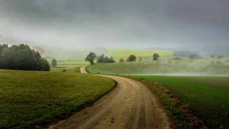 Serene Country Road Under Cloudy Skies wallpaper
