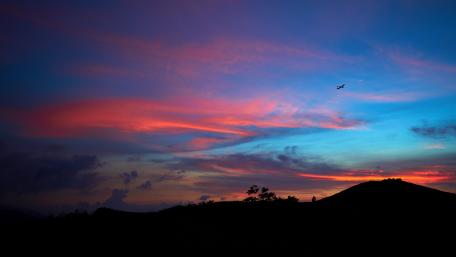 Twilight Flight Over Silhouetted Hills wallpaper