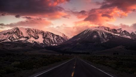 Serene Highway through Majestic Mountains at Sunset wallpaper
