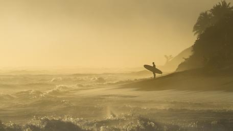 Surfes with surfboard and the surging sea wallpaper