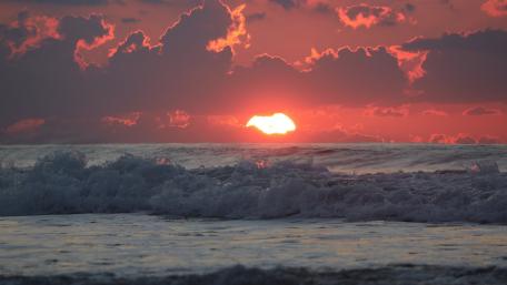 Vibrant Sunset Over Rolling Waves wallpaper