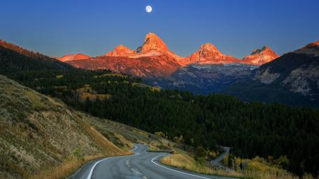 Winding Road Through Majestic Mountains Under Moonlight wallpaper