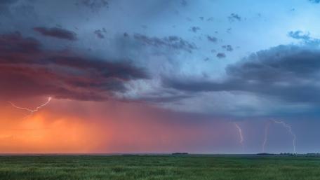 Dramatic Storm Over a Serene Grassland wallpaper