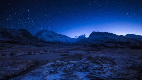 Starry night sky above the snowy mountains wallpaper