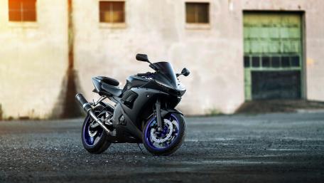 Sleek Black Motorcycle Front of Warehouse wallpaper