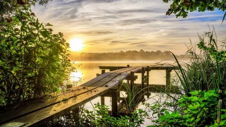 Tranquil Sunrise Over Riverside Pier Scene wallpaper