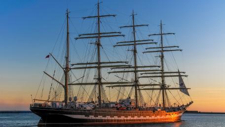 Majestic Tall Ship Sailing in Golden Hour Light wallpaper
