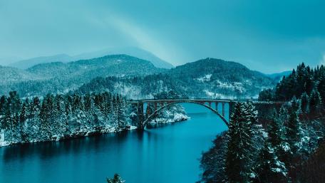 Serene Blue Winter Landscape with Bridge and Mountains wallpaper