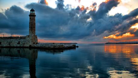Lighthouse Glow Under Cloudy Sky wallpaper