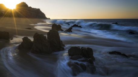 Serene Sunset Over Rocky Shoreline wallpaper