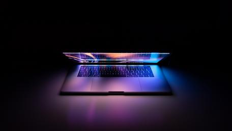 Laptop Illuminated with Dynamic Light Streams wallpaper