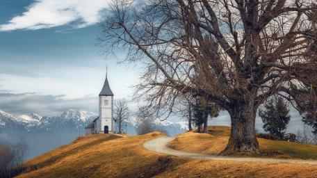 Serene Church Amidst Rolling Hills and Mountains wallpaper