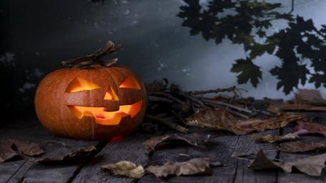 Eerie Jack-O'-Lantern Under Autumn Leaves wallpaper