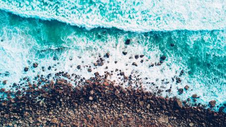 Emerald Waves Caressing Pebbled Shore wallpaper