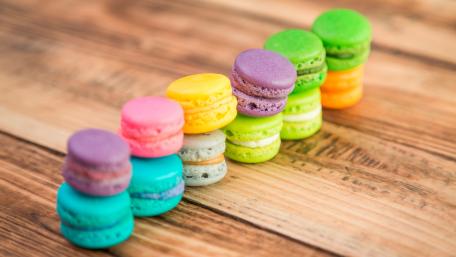 Vibrant Assortment of Macarons on Rustic Wood wallpaper