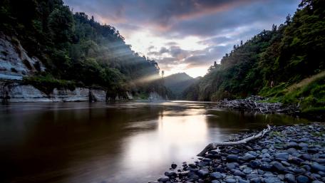 Stream under mountains and sunlight shadows wallpaper
