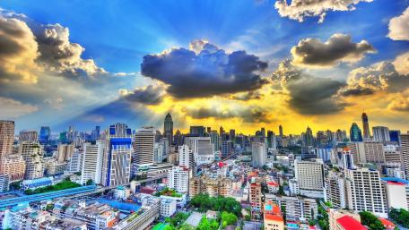 Rays of sunlight bursting through clouds above Bangkok City wallpaper