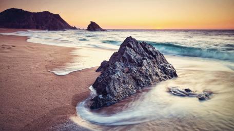 Serene Beach Sunset with Rocky Shoreline wallpaper