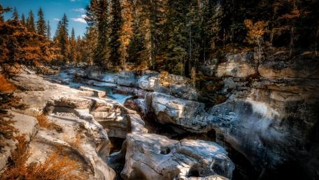 Serene River Carving Through Majestic Rocks in Autumn Colors wallpaper