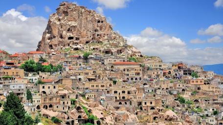 Majestic Cave Dwellings Amidst Rocky Peaks wallpaper
