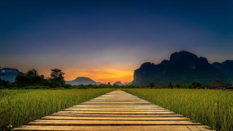 Serene Pathway Leading to Majestic Mountains at Dusk wallpaper