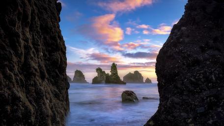 Serene Coastal Sunset Amidst Dramatic Rocks wallpaper