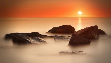 Tranquil Sunset Over Rocky Shoreline wallpaper