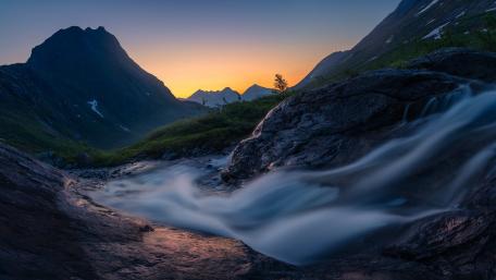 Serene Mountain Landscape at Dusk with Waterfall Flowing wallpaper