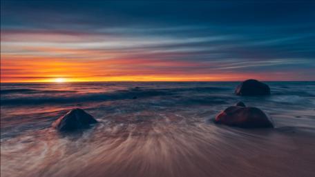 Tranquil Sunset Over Serene Sea and Boulders wallpaper