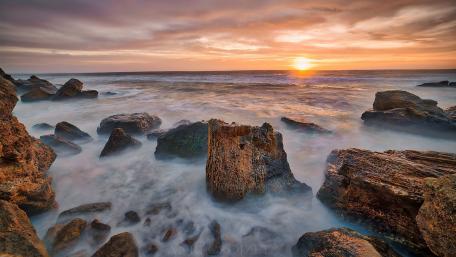 Serene Sunset Over Rocky Shoreline wallpaper