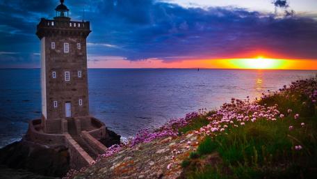 Serene Lighthouse at Sunset Over Tranquil Sea wallpaper