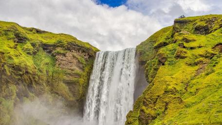 Majestic Waterfall Surrounded by Lush Greenery wallpaper