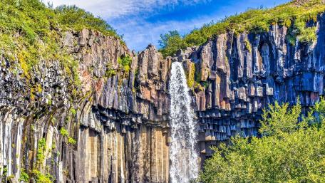 Majestic Waterfall Surrounded by Lush Greenery wallpaper
