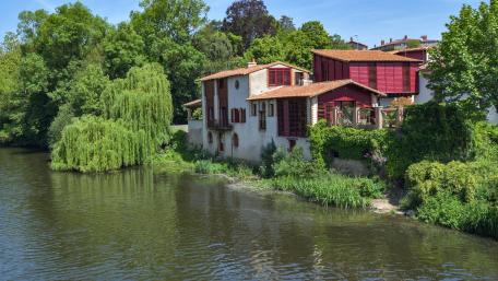 Serene Riverside Escape with Lush Greenery and Charming Architecture wallpaper