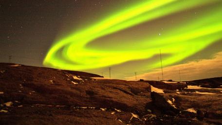 Dazzling Green Auroras Over Rocky Terrain wallpaper
