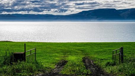 Tranquil Lakeside Landscape with Rolling Hills and Cloudy Sky wallpaper