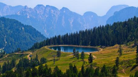 Tranquil Mountain Lake Surrounded by Lush Forests and Peaks wallpaper