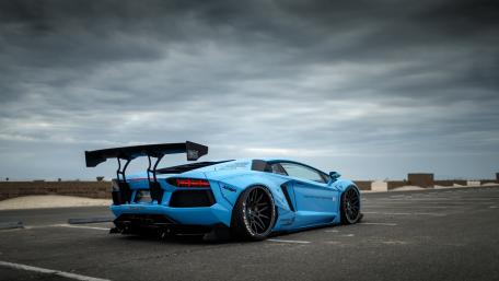 Sleek Blue Supercar Under Dramatic Sky wallpaper