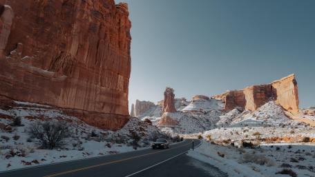 Majestic Winter Road Beside Towering Cliffs wallpaper