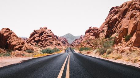 Vibrant Desert Road Amidst Striking Red Rocks wallpaper