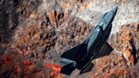 Futuristic Jet in Action Above Vibrant Landscape wallpaper