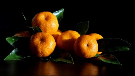 Vibrant Mandarins Glowing Against Dark Background wallpaper