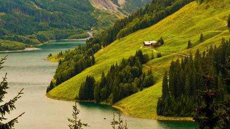 Serene Riverside Cottage Amidst Lush Hills wallpaper
