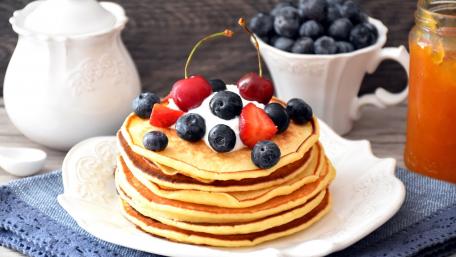 Delicious Stack of Pancakes Loaded with Berries and Creamy Topping wallpaper