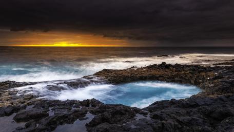 Tranquil Ocean Sunset Amidst Dark Clouds wallpaper