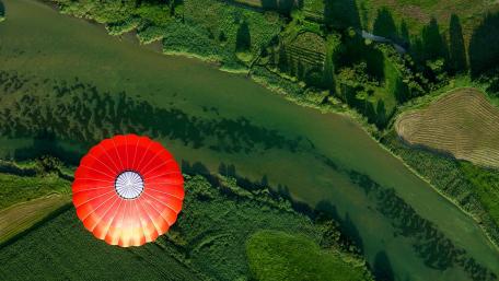Vibrant Parachute Over Serene River Landscape wallpaper