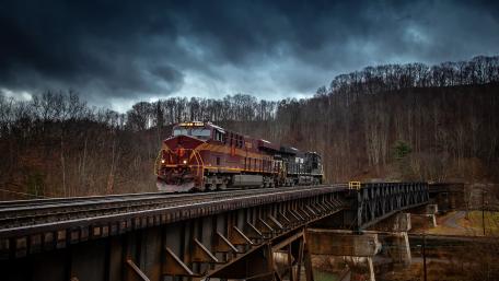 Majestic Train Crossing a Dramatic Bridge wallpaper