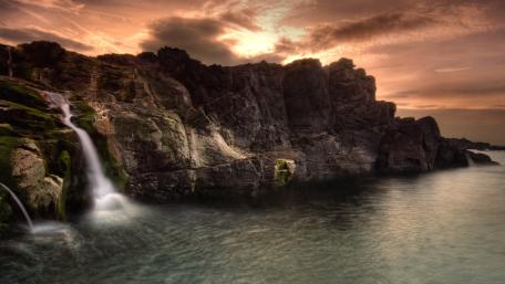 Majestic Waterfall Embraced by Sunset Glow wallpaper