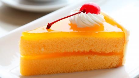 Delicious Orange Cake Slice with Cherry Topping wallpaper