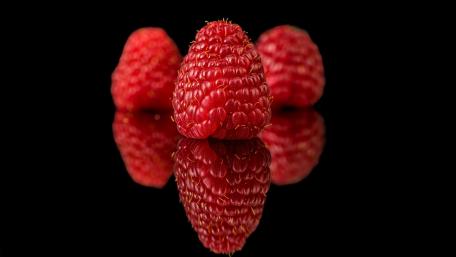Delicious Red Raspberries on a Glossy Surface wallpaper